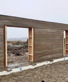 two open wooden doors on the side of a building being built with wood planks