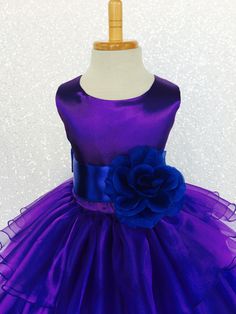 a purple and blue dress with a flower on the front, sitting on a mannequin