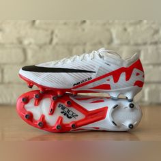 a pair of white and red shoes sitting on top of a wooden table