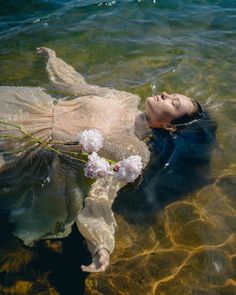 a woman floating in the water with flowers