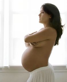 a pregnant woman standing in front of a window