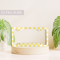 a yellow and white photo frame sitting on top of a table next to a potted plant