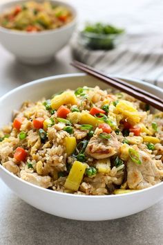 a bowl filled with rice and vegetables next to chopsticks on a table top