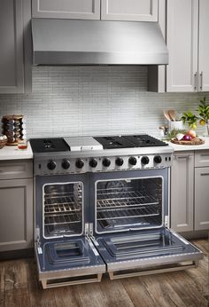 two ovens in the middle of a kitchen with white cabinets and wood flooring