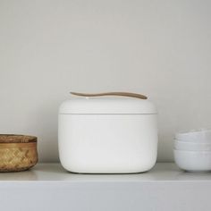 two bowls are sitting on a shelf next to an ice cream container and a wooden spoon