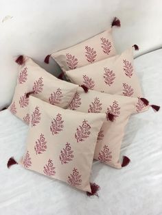 four pillows with tassels are on a bed