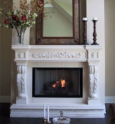 a fireplace with a mirror above it and flowers in vases on the mantel