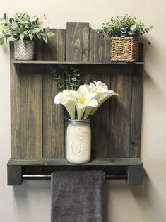 some flowers are sitting in a mason jar on a shelf with two towels hanging from it