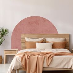 a bed with pillows and blankets on it in front of a pink circle headboard