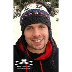 a man wearing a knitted hat and scarf with skis on his head smiling at the camera