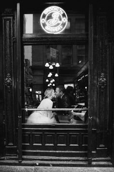 black and white photo of bride and groom kissing in front of the coffee shop window