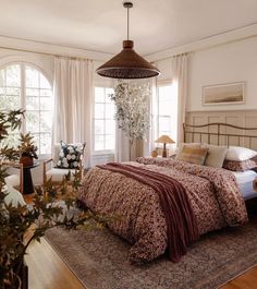 a bedroom with a large bed and two lamps hanging from it's ceiling above the bed