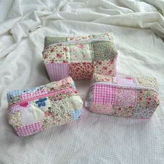 four pieces of pink and white quilted fabric on top of a bed covered in sheets