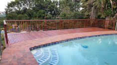 a wooden deck next to a swimming pool with steps leading up to the bottom level