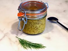 a jar filled with food sitting on top of a white counter next to a spoon