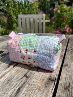 a small patchwork bag sitting on top of a wooden table next to a bench