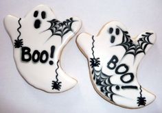 two decorated cookies with black and white icing on them that say boo or ghost