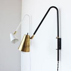 a black and gold lamp is on the wall next to a white wall with a light fixture