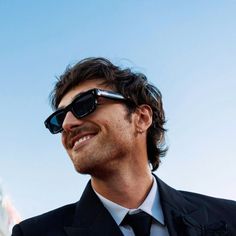 a man wearing sunglasses and a suit smiling