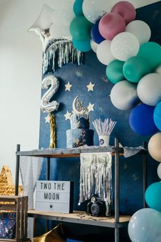 a birthday party with balloons, streamers and cake for two the moon on display