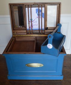 an open blue chest sitting on top of a hard wood floor next to a window