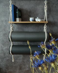 a shelf with two yoga mats hanging from it's sides and flowers in the foreground