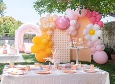 a table topped with balloons and plates under a tree