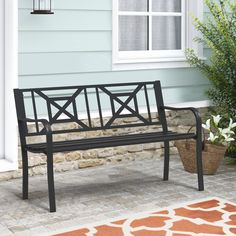 a black bench sitting in front of a house next to a potted green plant