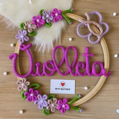 a wooden hoop with the word delta spelled out in crochet and decorated with flowers