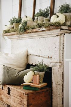 an old trunk is filled with pumpkins and greenery on the mantle in front of a mirror