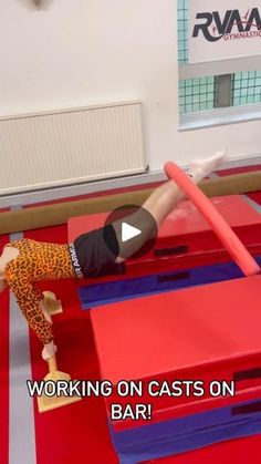 a man is doing tricks on an obstacle course in a gym with red and blue mats