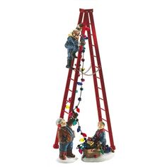 two figurines standing on top of a red ladder with christmas lights hanging from it