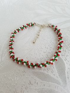 a red, green and white beaded bracelet on a lace tablecloth with a silver cross