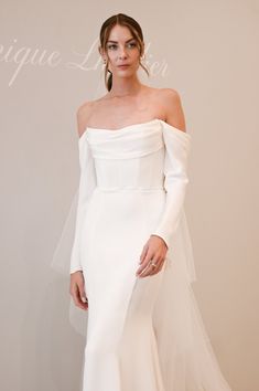 a woman in a white wedding dress standing next to a wall