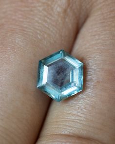 a close up of a person's hand with a ring on it and an aqua colored diamond in the middle