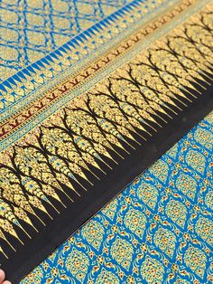 a person is holding an intricate blue and gold cloth