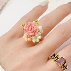 a woman's hand with two rings on it and a pink flower in the middle