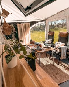 the inside of a camper with chairs, tables and windows looking out onto an open field