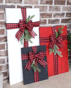 two christmas presents are sitting on a shelf next to a brick wall and decorated with greenery