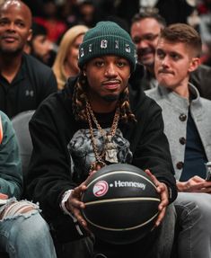 a man holding a basketball while sitting next to other people