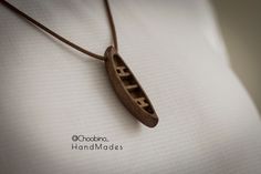 a wooden necklace with the word life carved into it's bottom half on a white shirt