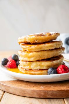 stack of pancakes with syrup and berries on a plate