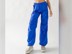 "Retro Parachute Cargo Pants.   Features Elastic Waist Band and Drawstring on waist and bottom hem. Cargo Style Y2K Light Weight Pants has Loose Baggy Fit and Side Flap Snap Pocket. Small (2/4), Medium (6/8), Large (10) Small waist is 27\" without stretch. medium: 28.5\" large: 30\" 100% Nylon  Pants are pretty comfortable fit but please size up if im doubt.  Model's wearing size small and her height is 5'7\" Color may vary slightly due to monitor resolution. Gentle Cycle, Hand Washing/Hang Dry 90s Style Baggy Parachute Pants, 90s Baggy Parachute Pants, 90s Style Stretch Streetwear Pants, 90s High Waist Parachute Pants For Streetwear, 90s High-waisted Parachute Pants For Streetwear, 90s Parachute Pants For Streetwear, 90s Parachute Pants With Cargo Pockets, Sporty High Waist Parachute Pants For Streetwear, 90s Style Nylon Bottoms For Streetwear