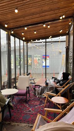 a room filled with lots of furniture next to tall glass windows on the side of a building