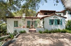 a white house with green shutters and trees