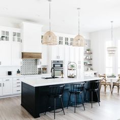 a large kitchen with white cabinets and black counter tops, along with bar stools