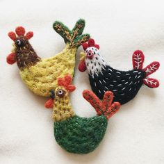 three crocheted roosters sitting next to each other on top of a white towel