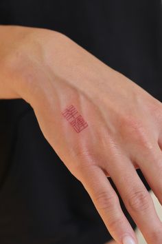 a woman's hand with a small red tattoo on her left thumb and fingers