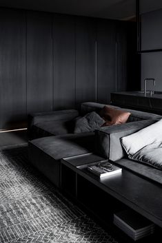 a living room filled with black furniture and pillows