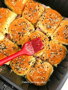 a plastic container filled with rolls covered in sesame seeds